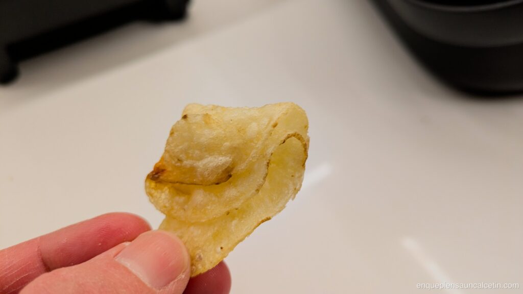 Una mano sujetando una patata frita doblada en cuatro capas.