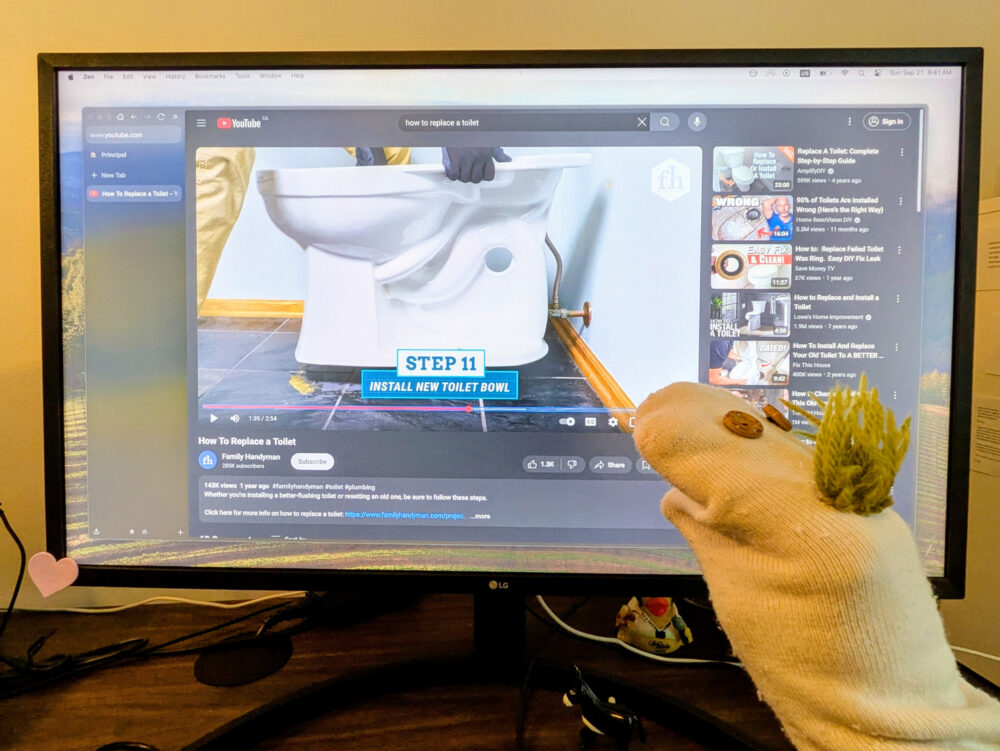 Marioneta de calcetín mirando un vídeo en Internet sobre cómo cambiar un váter.