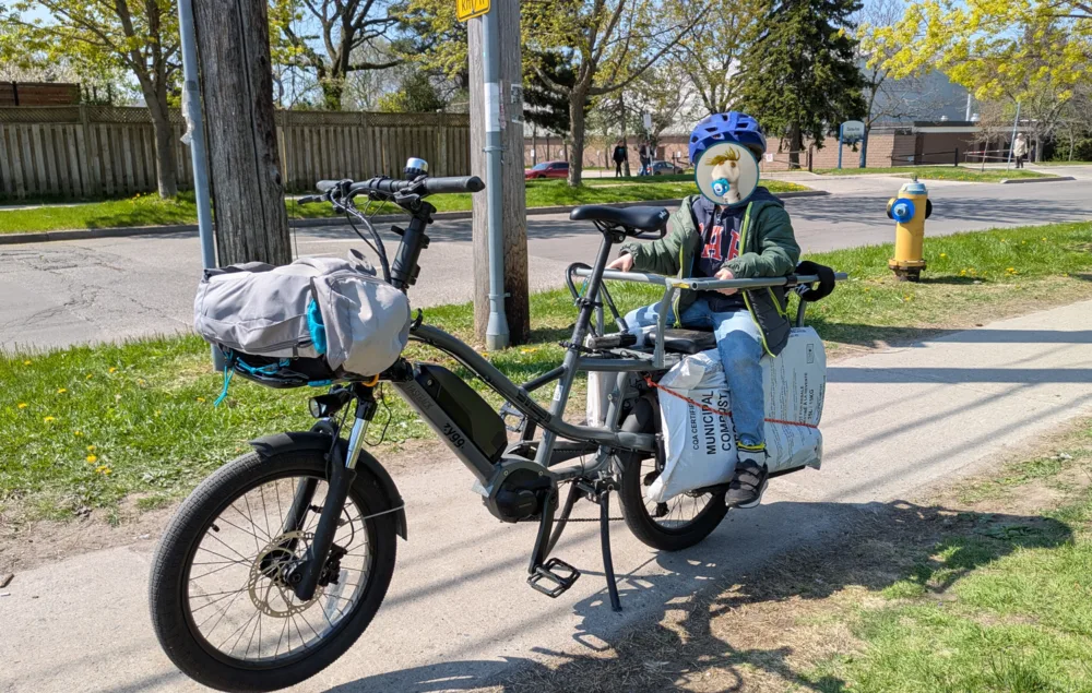 bicicleta eléctrica con niño de pasajero y cargando bolsas de compost